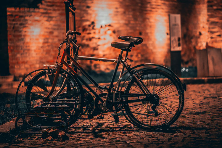 Bicycle parked against wall at night