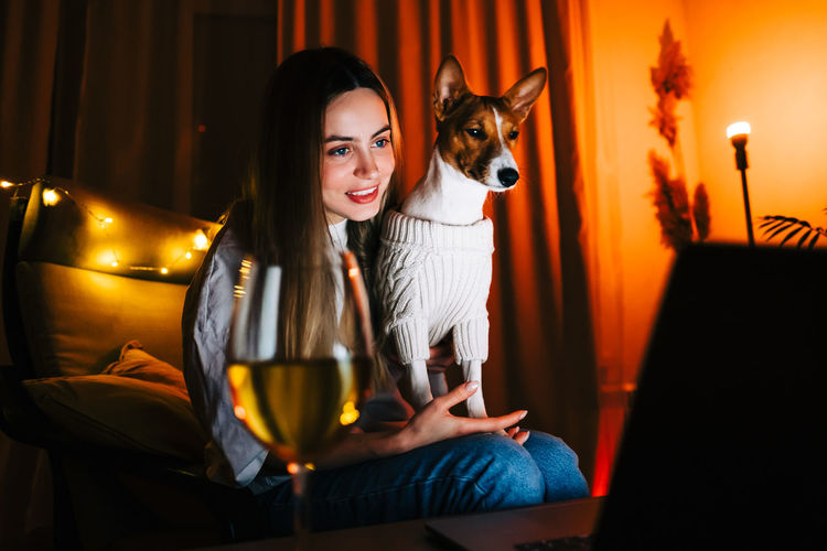 Portrait of smiling young woman sitting at home with dog