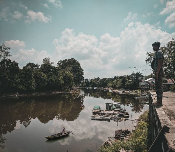 People by lake against sky