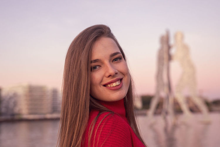 Portrait of smiling young woman against clear sky during sunset