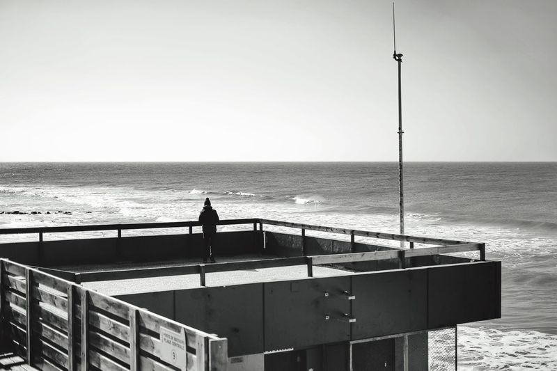 Rear view of person standing pier over sea