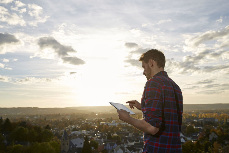 Man using tablet on a hill above a town