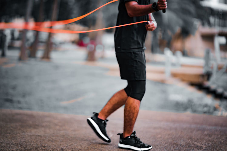 Blurry photo of fitness concept. healthy lifestyle. man in black holding skipping rope in the park.