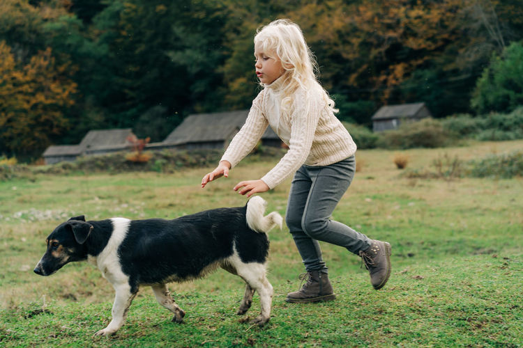 Little girl walking in the village with her dog.