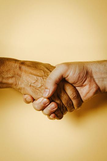 Close-up of handshake over yellow background