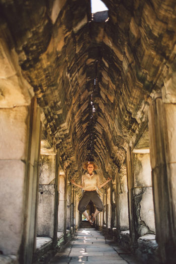 Woman levitating in corridor of historic building