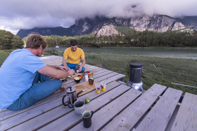 Two people having breakfast outside on roof of school bus scenic view