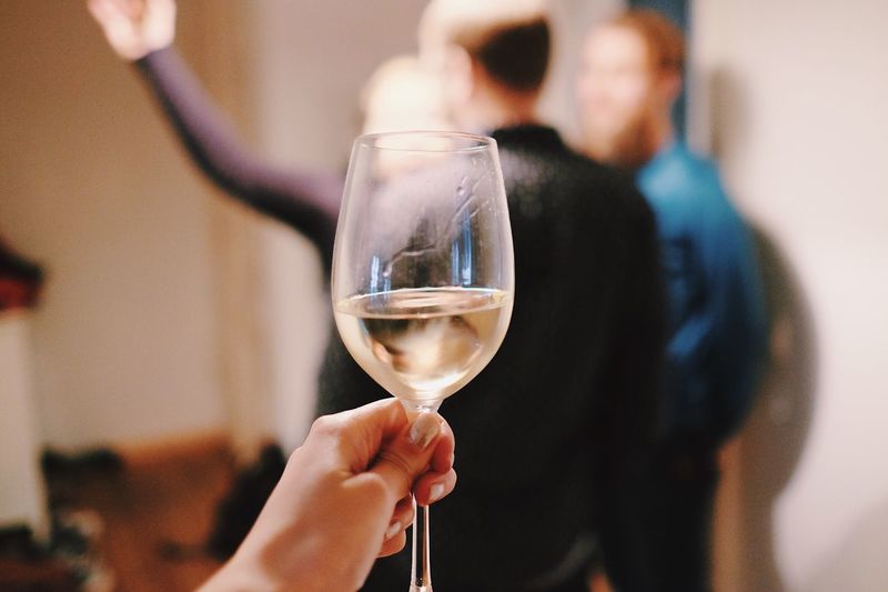 Cropped hand of woman holding white wine