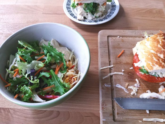 High angle view of pepperoni sandwich with vegetable bowl on kitchen table