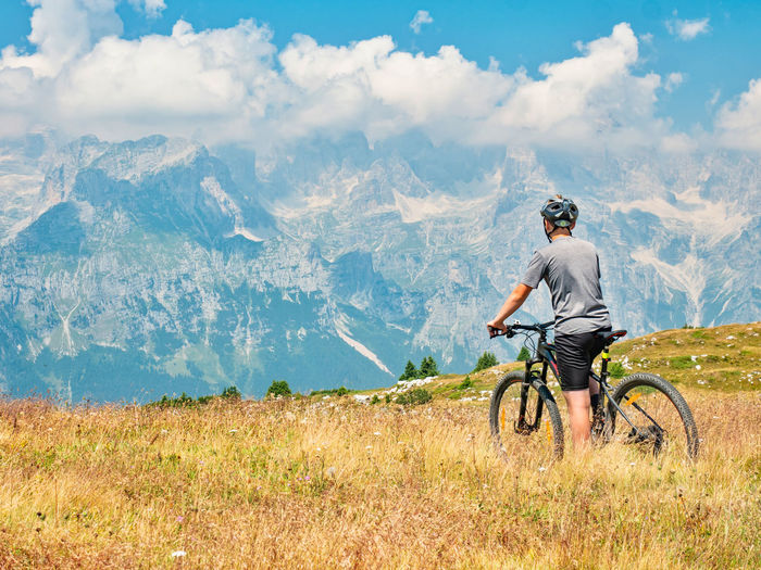 Teenager sit on modern mtb and watching from hill peak to peaks. dolomite alps, trento region, italy