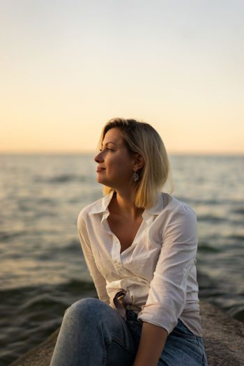 Portrait of middle aged woman standing at the beach at sunset