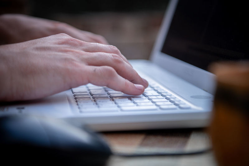 Close-up view of male hands working on laptop outside the house. a businessman works on  notebook 