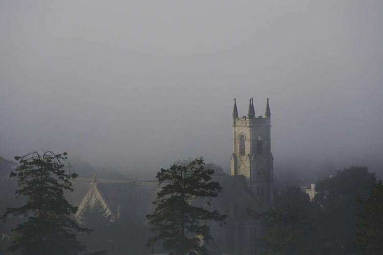 Church tower emerging from fog on a sunny morning