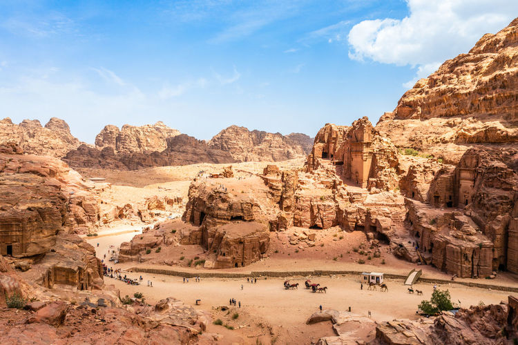 View to the ancient nabataean royal tombs and main street of petra full of tourist, jordan